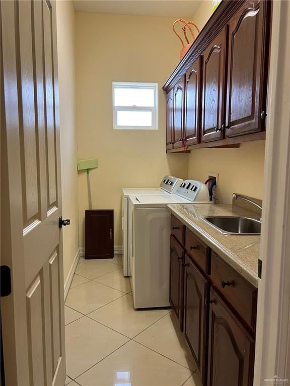 laundry area with light tile patterned floors, cabinet space, a sink, washer and dryer, and baseboards