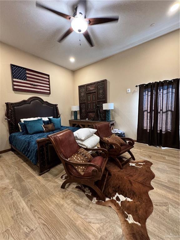 bedroom with ceiling fan, a textured ceiling, and light wood-type flooring