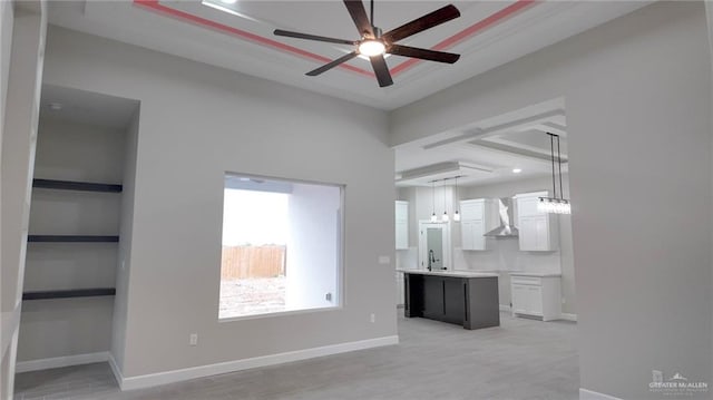 unfurnished living room with light wood-type flooring, ceiling fan, and sink