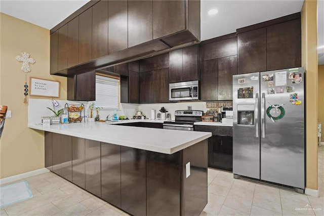 kitchen featuring kitchen peninsula, dark brown cabinets, stainless steel appliances, and light tile patterned floors