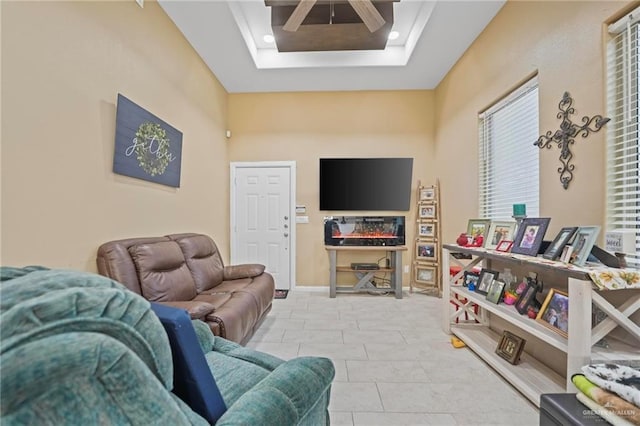 tiled living room with ceiling fan, a raised ceiling, and a wealth of natural light