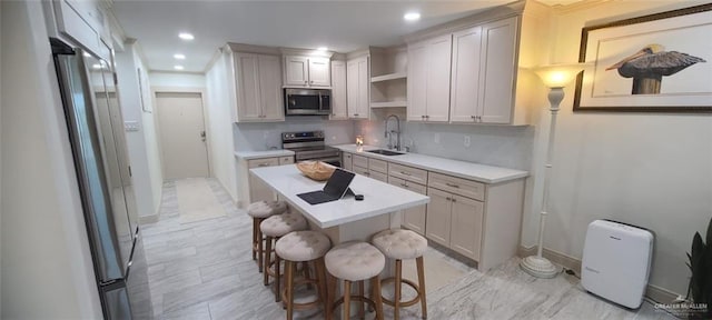 kitchen with a kitchen breakfast bar, sink, a kitchen island, and appliances with stainless steel finishes