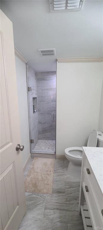 bathroom featuring a shower with door, vanity, and toilet