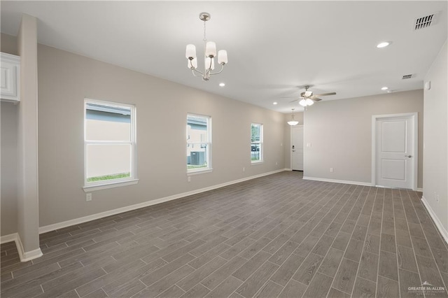 spare room featuring ceiling fan with notable chandelier and a healthy amount of sunlight