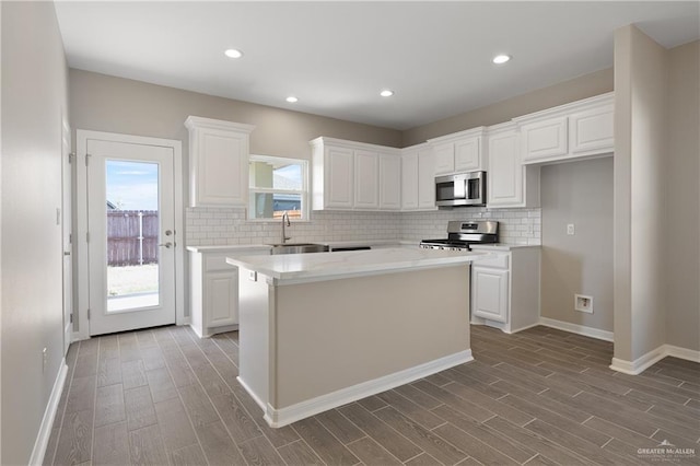 kitchen with sink, stainless steel appliances, a kitchen island, light hardwood / wood-style flooring, and white cabinets