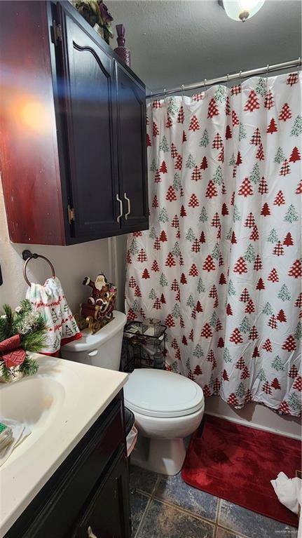 bathroom featuring a textured ceiling, vanity, and toilet