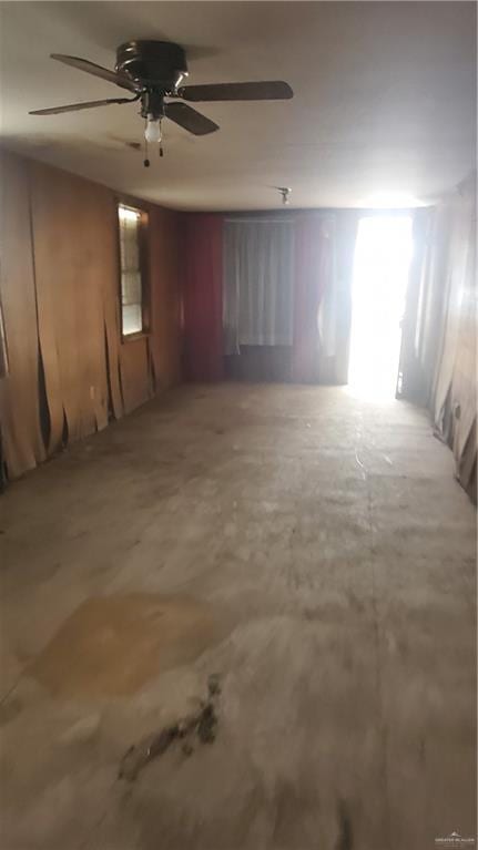 empty room with ceiling fan and concrete flooring