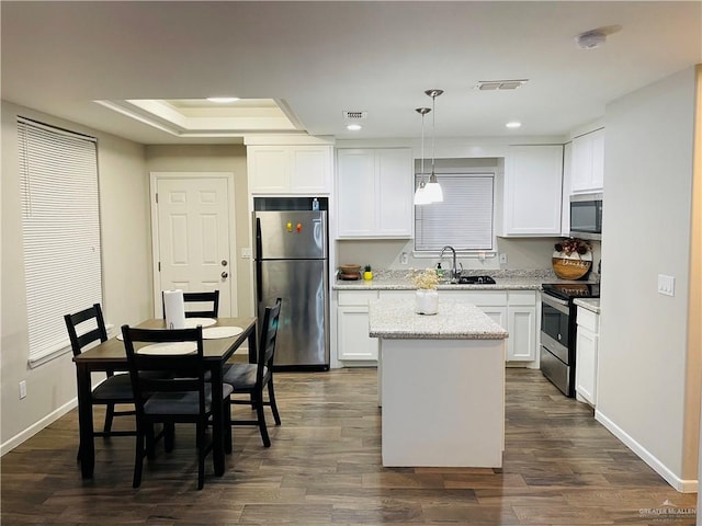 kitchen with appliances with stainless steel finishes, white cabinetry, hanging light fixtures, and sink