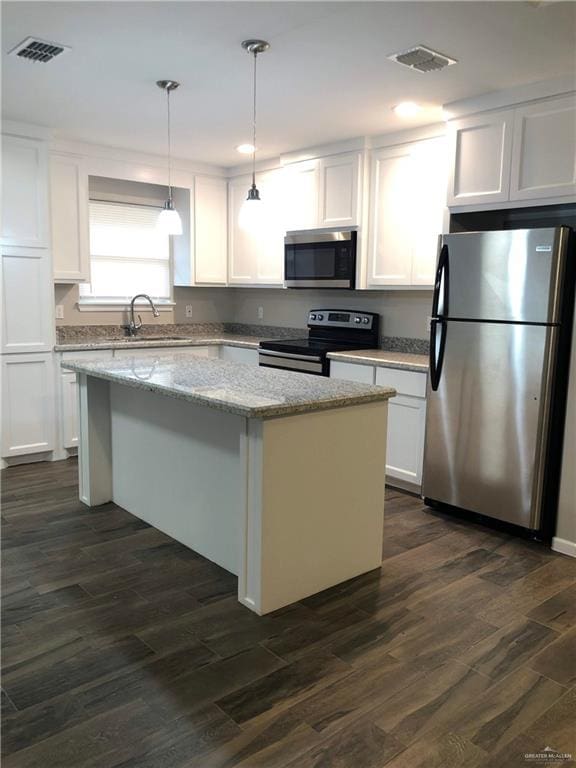 kitchen with pendant lighting, a center island, appliances with stainless steel finishes, dark hardwood / wood-style flooring, and white cabinetry