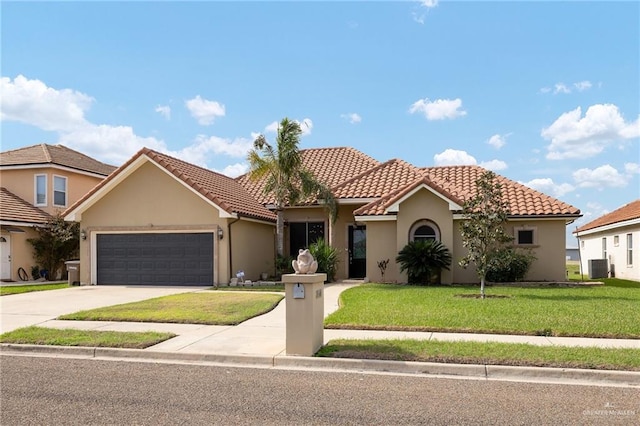 mediterranean / spanish house with driveway, stucco siding, a tiled roof, an attached garage, and a front yard