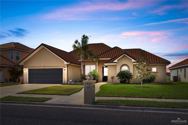 view of front facade featuring driveway, a lawn, an attached garage, and stucco siding