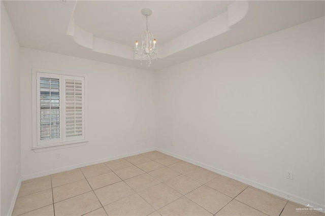 507 Edgewood Ave, Edinburg, TX 78541 - empty room with light tile patterned floors, a tray ceiling, a notable chandelier, and baseboards