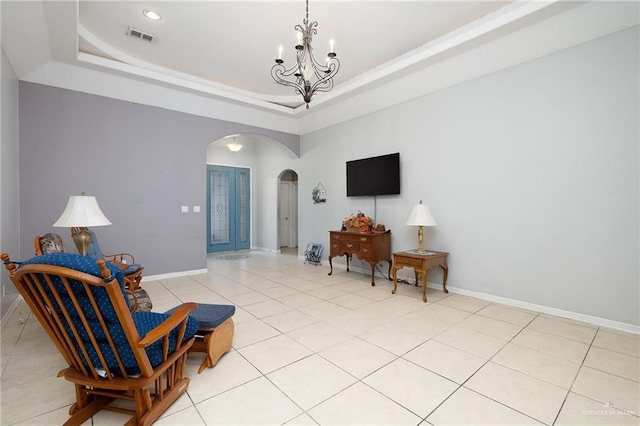 living area featuring a tray ceiling, french doors, light tile patterned floors, and an inviting chandelier