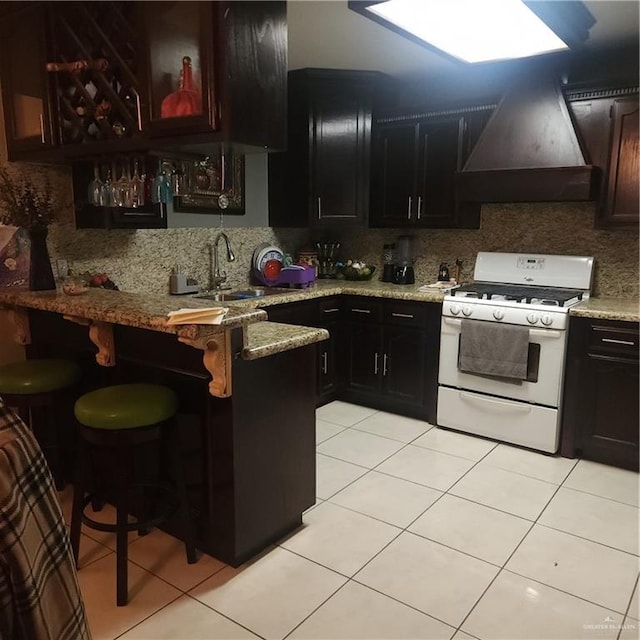 kitchen with custom exhaust hood, sink, gas range gas stove, and light tile patterned floors