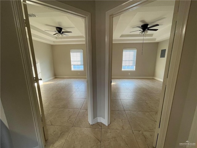 spare room with a raised ceiling, ceiling fan, and baseboards