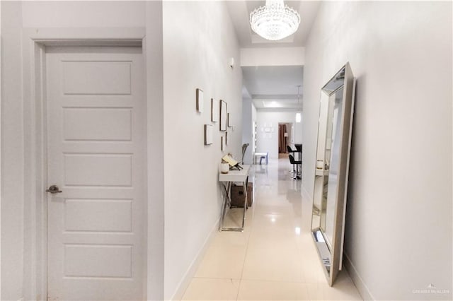 hallway with light tile patterned floors and a notable chandelier