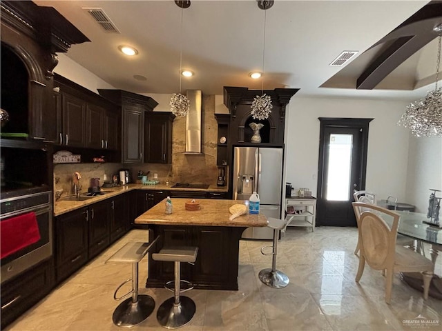 kitchen with stainless steel refrigerator with ice dispenser, visible vents, wall chimney exhaust hood, and a sink