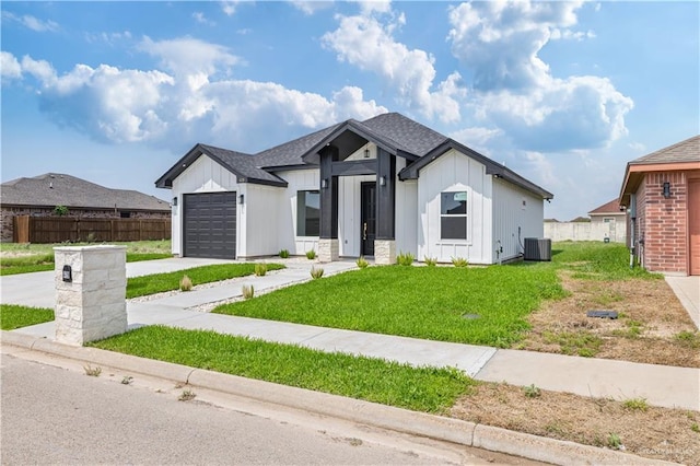 modern farmhouse with concrete driveway, fence, board and batten siding, and a garage
