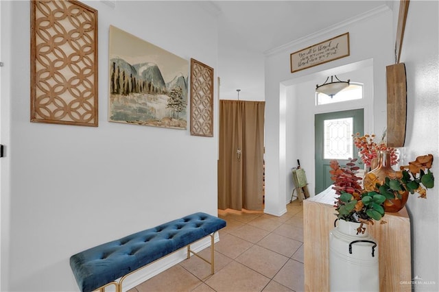 foyer entrance with light tile patterned floors and crown molding