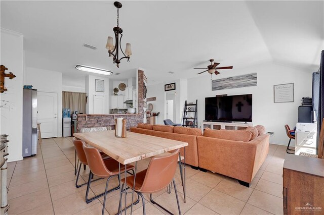 dining area with light tile patterned floors, visible vents, vaulted ceiling, and ceiling fan with notable chandelier