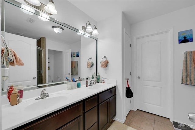 full bath with tile patterned flooring, a stall shower, double vanity, and a sink