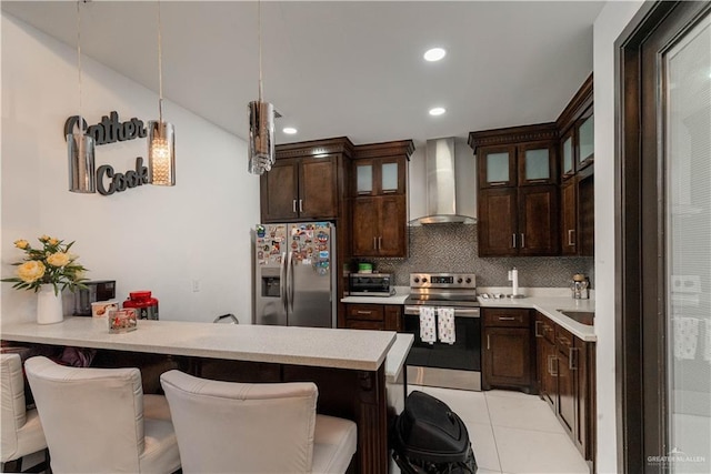 4000 Eucaliptus Ave, Mcallen, TX 78501 - kitchen featuring wall chimney range hood, stainless steel appliances, a breakfast bar, a peninsula, and dark brown cabinetry