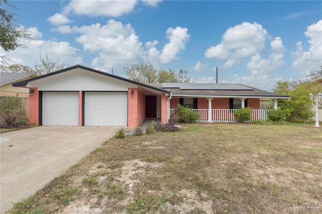 ranch-style house with a garage, a front lawn, covered porch, and solar panels