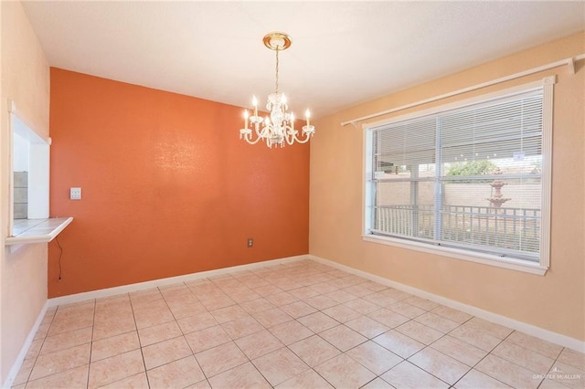 tiled empty room featuring an inviting chandelier