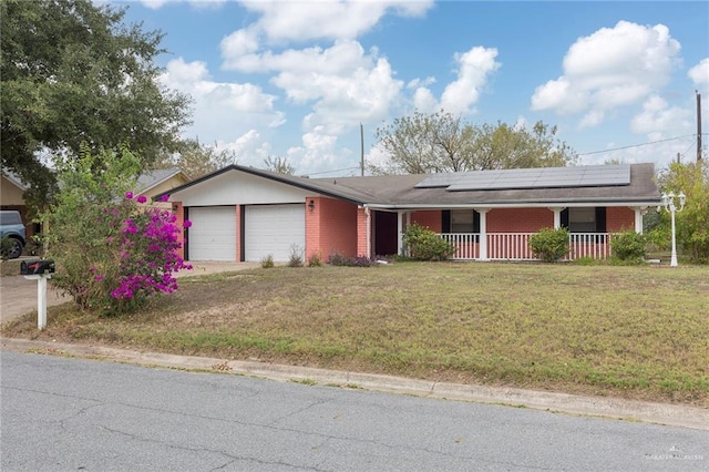 single story home featuring a porch, a garage, a front lawn, and solar panels