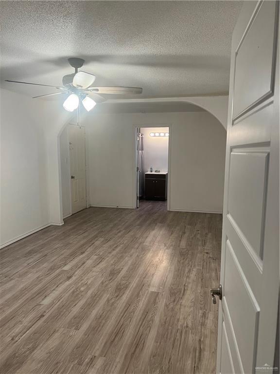 spare room featuring a textured ceiling, wood-type flooring, and ceiling fan