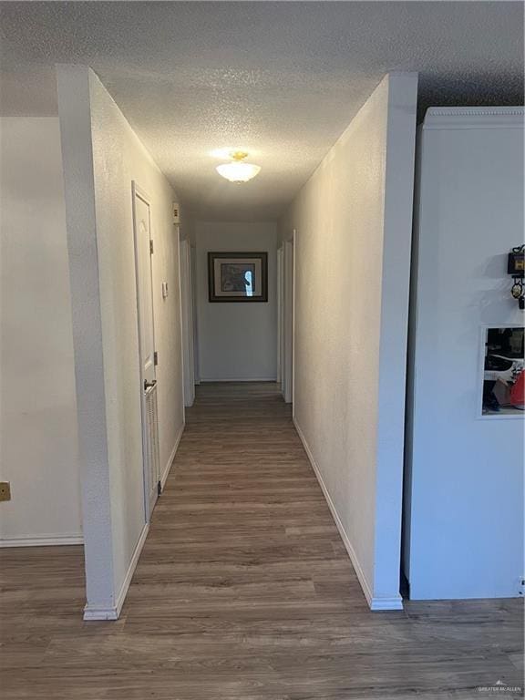 hallway with hardwood / wood-style floors and a textured ceiling