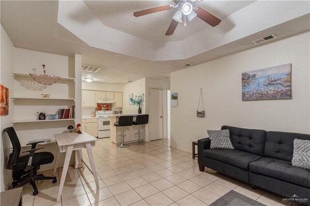 tiled living room with a textured ceiling, a raised ceiling, and ceiling fan