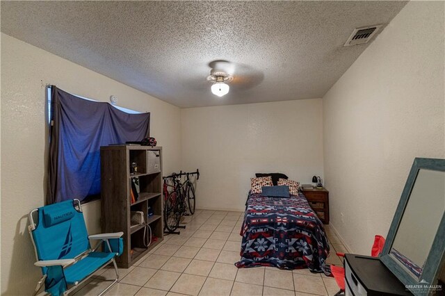 bedroom with ceiling fan, light tile patterned floors, and a textured ceiling