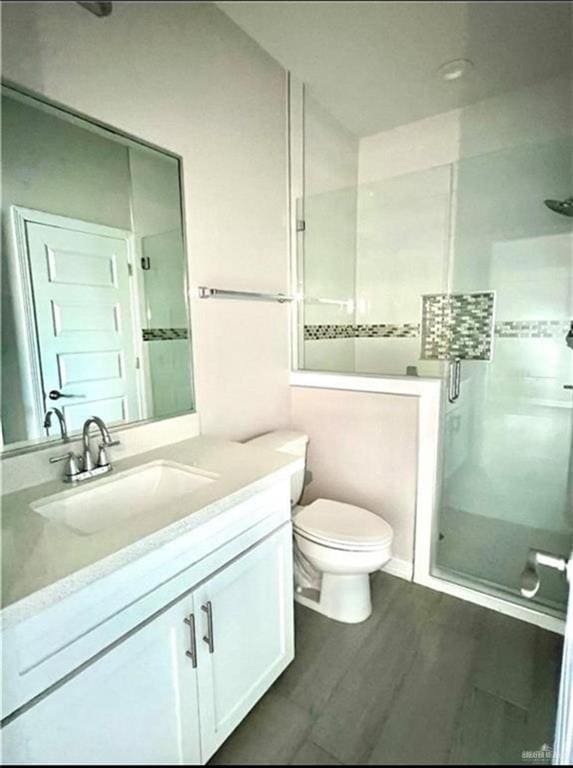 bathroom featuring vanity, toilet, hardwood / wood-style floors, and walk in shower