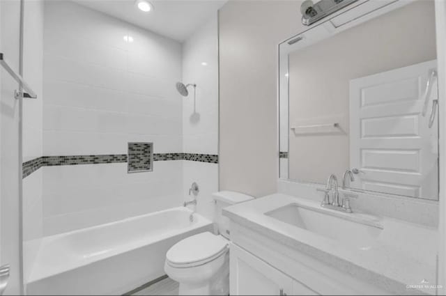 full bathroom featuring tiled shower / bath, vanity, and toilet