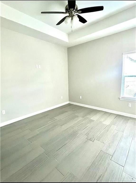 spare room with a tray ceiling and ceiling fan