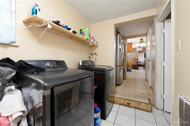 washroom with laundry area, light tile patterned floors, heating unit, a textured ceiling, and washer and dryer