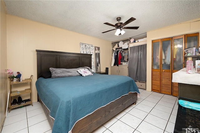 bedroom with a ceiling fan, a textured ceiling, two closets, and light tile patterned floors