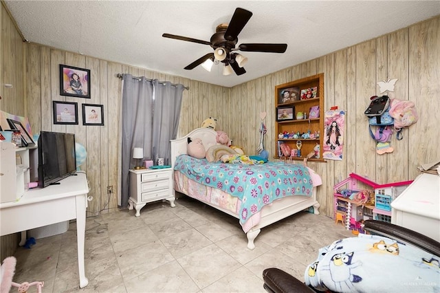 bedroom featuring ceiling fan, wood walls, and a textured ceiling