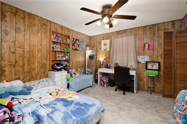 bedroom featuring a textured ceiling, wood walls, and a ceiling fan