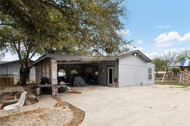 back of property featuring an attached carport, concrete driveway, a patio area, and fence