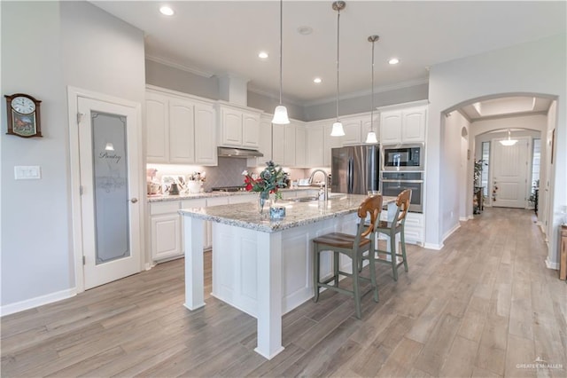 kitchen featuring white cabinets, sink, light stone countertops, appliances with stainless steel finishes, and decorative light fixtures