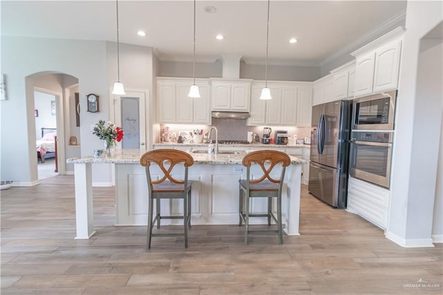 kitchen featuring white cabinets, stainless steel appliances, light stone counters, and hanging light fixtures