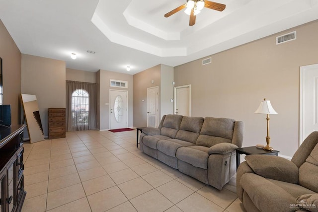 tiled living room featuring ceiling fan and a tray ceiling