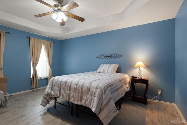 bedroom featuring a raised ceiling, ceiling fan, and hardwood / wood-style floors