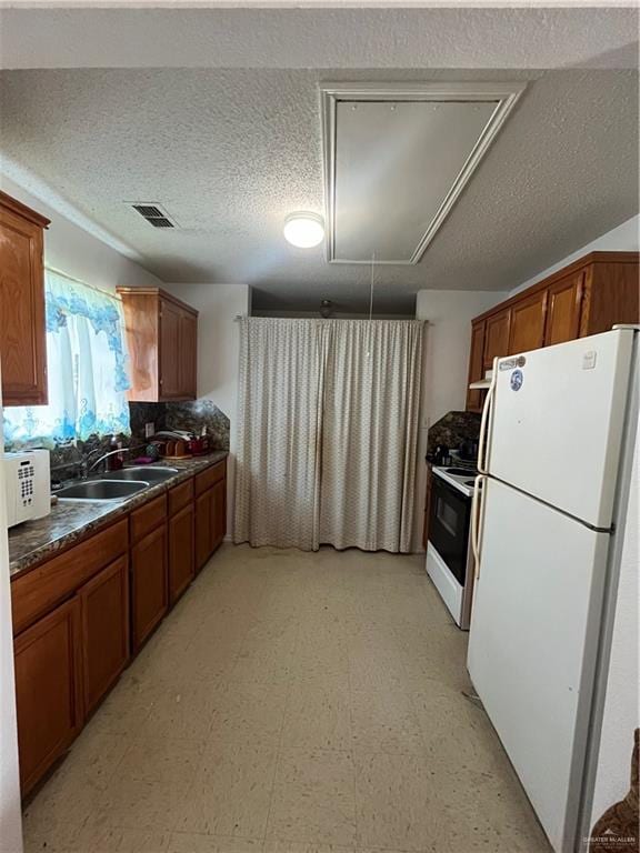 kitchen with a textured ceiling, white appliances, and sink