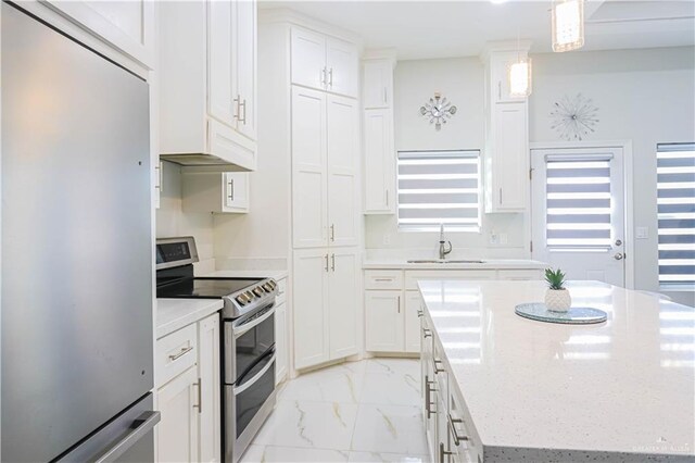 kitchen featuring a center island, white cabinets, sink, appliances with stainless steel finishes, and decorative light fixtures