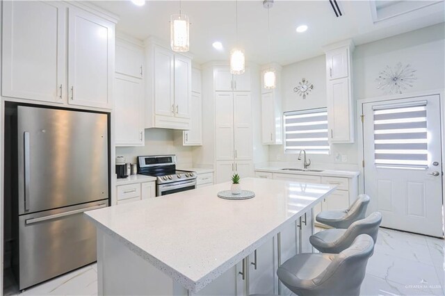 kitchen featuring white cabinets, stainless steel appliances, a kitchen island, and sink