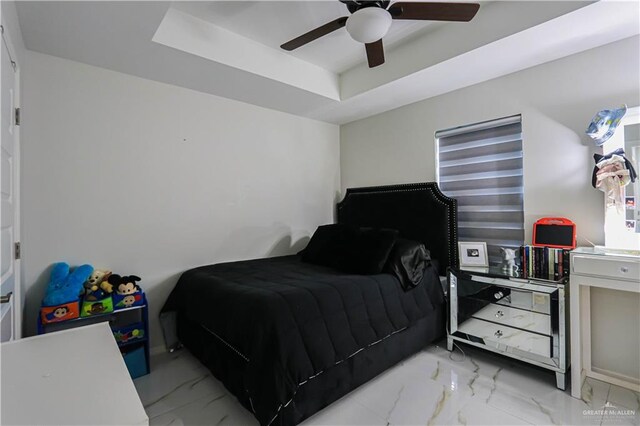 bedroom with ceiling fan and a raised ceiling