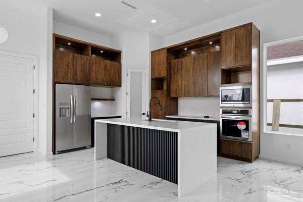 kitchen with dark brown cabinetry, sink, a center island with sink, and appliances with stainless steel finishes